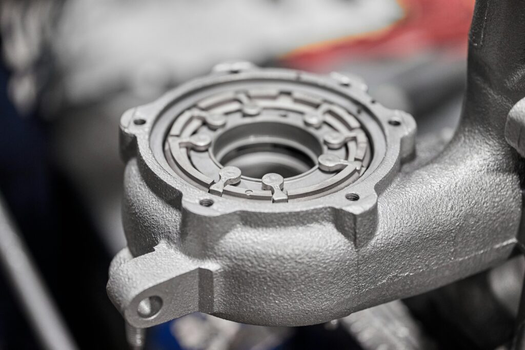 pexels-photo-14522449-14522449 Detailed image of a metallic car component in a workshop setting, highlighting intricate metalwork.